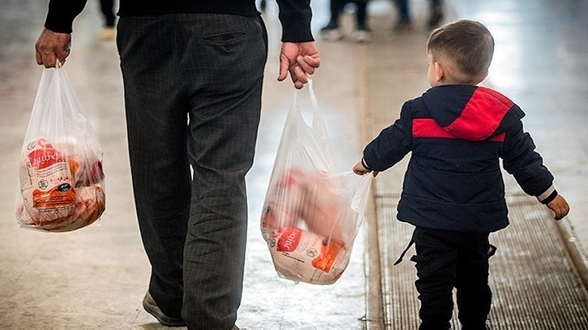 یک مرد ایرانی  در حال حمل دو بسته مرغ زیر قیمت. تهران، ایران.  ۲۶ اسفند ۱۳۹۹. (عکس از عرفان کوچاری از خبرگزاری تسنیم)