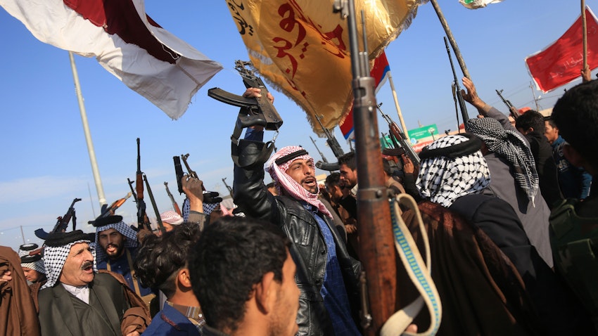 Armed tribesmen lift their guns amidst ongoing anti-government protests in southern Iraq on Dec. 8, 2019. (Photo via Getty Images)