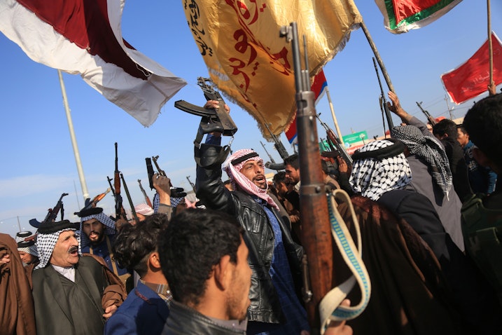 Armed tribesmen lift their guns amidst ongoing anti-government protests in southern Iraq on Dec. 8, 2019. (Photo via Getty Images)