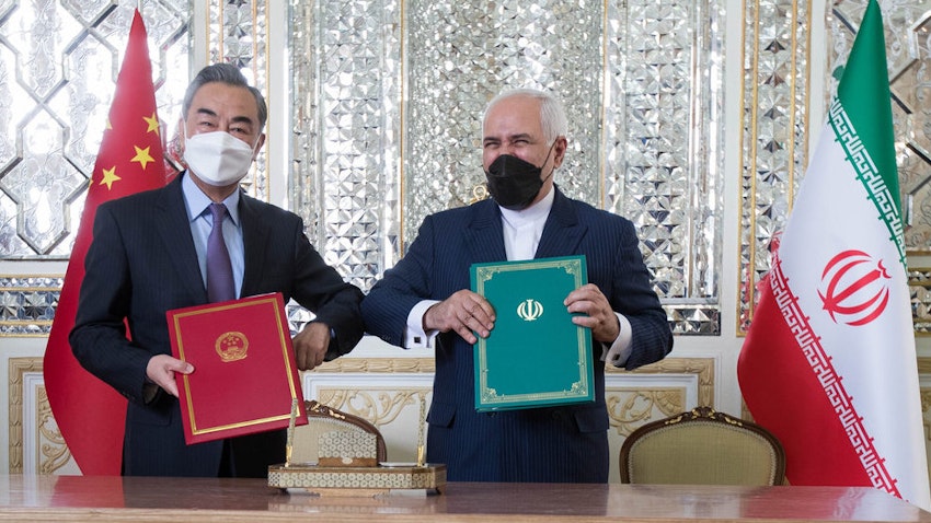  Iran’s foreign minister (right) and his Chinese counterpart pose for a photo after signing a 25-year cooperation agreement in Tehran. (Photo by Mohammadreza Abbasi via Mehr News Agency)