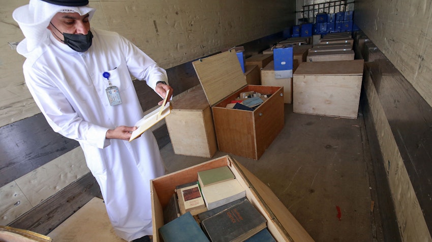 موظف حكومي في مدينة الكويت يعاين صناديق تحتوي على مواد من الأرشيف صودرت أثناء غزو العراق للكويت في عام 1990، في 28 مارس/آذار 2021. (الصورة عبر غيتي إيماجز)