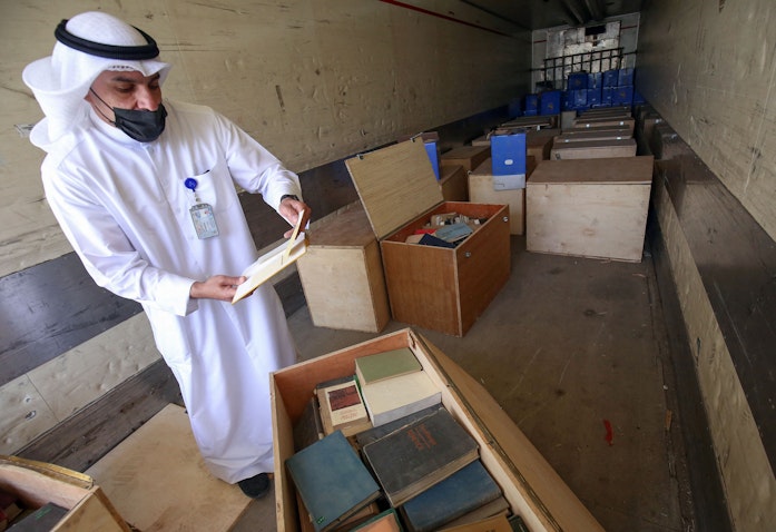 موظف حكومي في مدينة الكويت يعاين صناديق تحتوي على مواد من الأرشيف صودرت أثناء غزو العراق للكويت في عام 1990، في 28 مارس/آذار 2021. (الصورة عبر غيتي إيماجز)