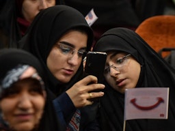 Two Iranian students look at a cellphone during a summit in Allame Tabatabi University. Tehran, Iran. Dec. 7, 2019. (Photo by Behnam Tofiqi Forouhar via Mehr News Agency)
