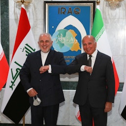 وزير الخارجية الإيراني محمد جواد ظريف (إلى اليسار) يحيي نظيره العراقي فؤاد حسين في بغداد في 26 نيسان/أبريل، 2021. (الصورة عبر غيتي إيماجز)