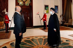 رئيس المحكمة العليا في إيران آنذاك إبراهيم رئيسي (إلى اليمين) يلتقي الرئيس العراقي برهم صالح في بغداد. 10 فبراير/ شباط 2021 (الصورة من وكالة ميزان للأنباء)