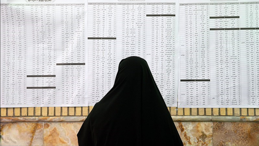 An Iranian woman looks at the list of city council candidates at a polling station in Tehran, Iran on June 18, 2021. (Photo via Tasnim News Agency)