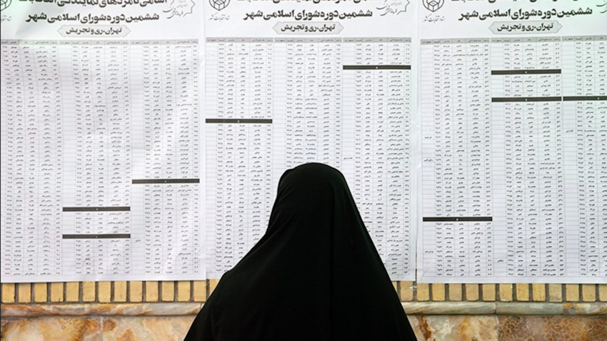 زنی ایرانی، در حال خواندن فهرست نامزدهای شورای شهر در یکی از مراکز رأی‌گیری در تهران؛ ایران، ۲۸ خرداد ۱۴۰۰. (عکس از خبرگزاری تسنیم)