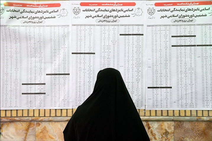 An Iranian woman looks at the list of city council candidates at a polling station in Tehran, Iran on June 18, 2021. (Photo via Tasnim News Agency)