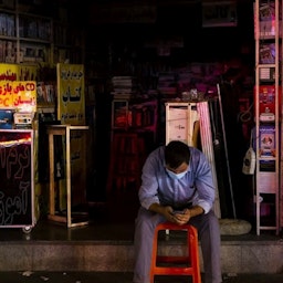 An Iranian sitting outside his store during a blackout in Tehran on July 5, 2021. (Photo by Mahdi Dorani via Fars News Agency)