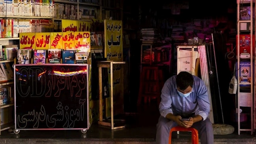 یک ایرانی که در هنگام قطعی برق در بیرون از مغازه اش در تهران نشسته است؛ ۱۴ تیر ۱۴۰۰. (عکس از مهدی دورانی/  خبرگزاری فارس)