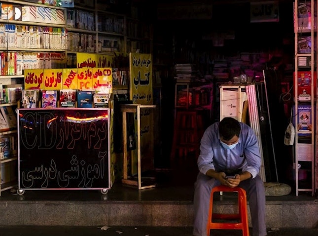 یک ایرانی که در هنگام قطعی برق در بیرون از مغازه اش در تهران نشسته است؛ ۱۴ تیر ۱۴۰۰. (عکس از مهدی دورانی/  خبرگزاری فارس)