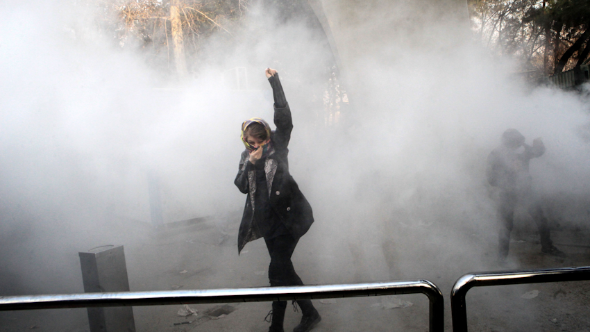 زن ایرانی که در اعتراض به مشکلات اقتصادی، مشت خود را در میان ابری از گاز اشک آور گره کرده است؛ تهران، ایران، ۹ دی ۱۳۹۶. (عکس از گتی ایمیجز)