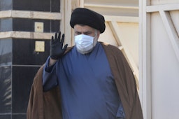 مقتدی صدر، روحانی و سیاستمدار عراقی، خارج خانه‌ی خود در شهر مقدس نجف دست تکان می‌دهد؛ عراق، ۲۲ بهمن ۱۳۹۹/ ۱۰ فوریه ۲۰۲۱. (عکس از گتی ایمیجز)