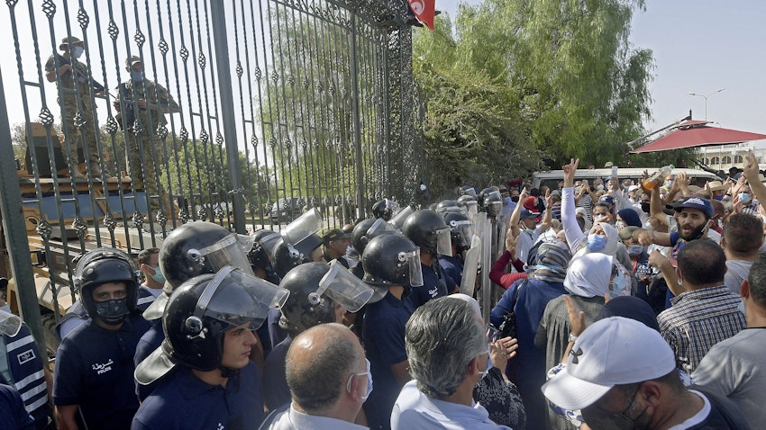 Tunisian security forces hold back protesters outside the parliament building in Tunis on July 26, 2021. (Photo via Getty Images)