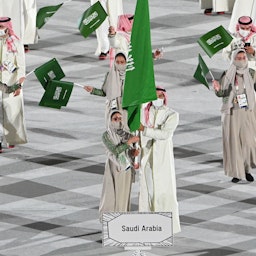 لاعبة الجودو السعودية تهاني القحطاني (إلى اليسار) تترأس وفد بلادها في حفل افتتاح أولمبياد طوكيو. 23 يوليو /تموز 2021 (الصورة عبر غيتي إيماجز)