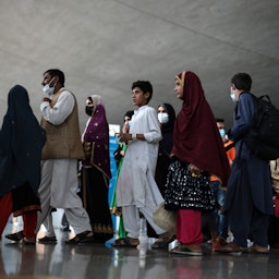 لاجئون أفغان يسيرون في محطة للمغادرة في مطار دالاس الدولي في فيرجينيا، الولايات المتحدة الأميركية في 31 أغسطس/ آب 2021 (الصورة عبر غيتي إيماجز)