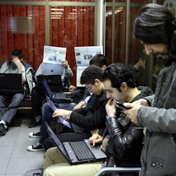 سرمایه‌گذاران ایرانی، در حال بررسی قیمت سهام در بورس اوراق بهادار تهران؛ ۲۴ دی ۱۳۹۲. (عکس از گتی ایمیجز)