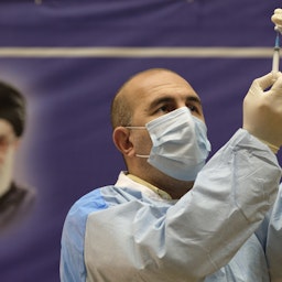 عامل صحي إيراني يملأ حقنة بلقاح كوفيد-19 في حفل لبدء التطعيم العام في طهران. 9 فبراير/شباط 2021 (الصورة عبر غيتي إيماجز)