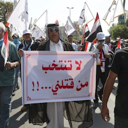 یک مرد عراقی پلاکاردی در دست دارد که روی آن نوشته شده است "به کسانی که ما را کشتند رأی ندهید" در تظاهرات در بغداد؛ عراق، ۹ مهر ۱۴۰۰/ ۱ اکتبر ۲۰۲۱. (عکس از گتی ایمیجز)
