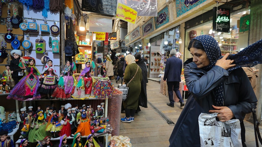 A woman looks at dolls in local costumes displayed outside a shop at the Tajrish bazar in Tehran on Apr. 23, 2019. (Photo via Getty Images)