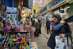 زنی در حال تماشای عروسک‌هایی با لباس محلی در بازار تجریش تهران؛ ۳ ارديبهشت ۱۳۹۸. (عکس از گتی ایمیجز)