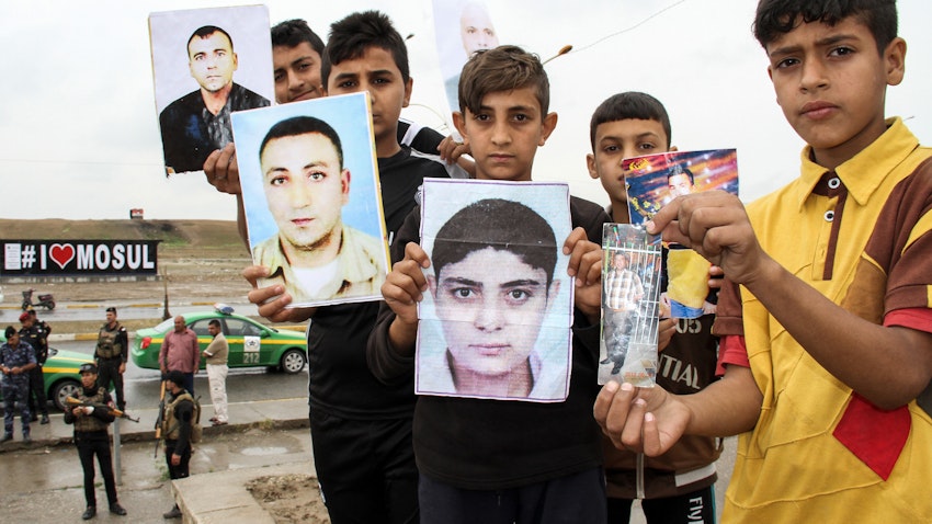 عراقيون يحملون صورًا لأقاربهم المفقودين الذين احتجزهم تنظيم الدولة الإسلامية خلال مظاهرة في الموصل، العراق. 13 أبريل/نيسان، 2018 (الصورة عبر غيتي إيماجز)