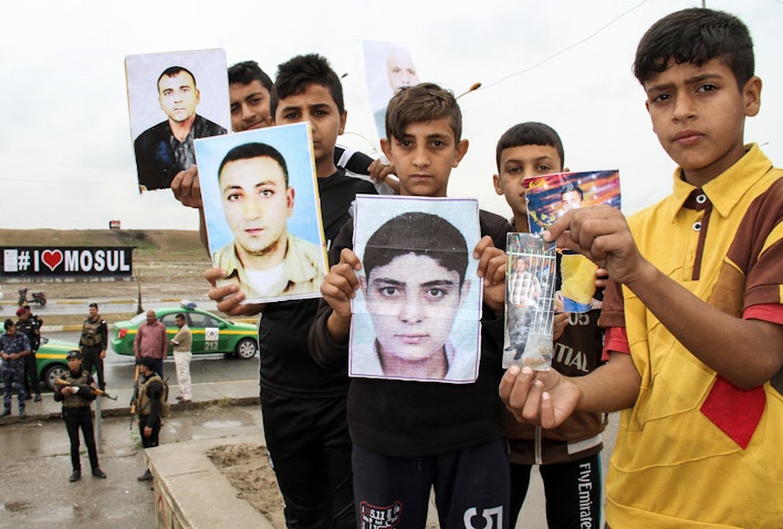 Iraqis hold up portraits of missing relatives who were held captive by the Islamic State group during a demonstration in Mosul, Iraq on Apr. 13, 2018. (Photo via Getty Images)