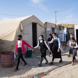 Girls walk to class on the first day of school in a Yazidi displacement camp near the northern city of Dohuk in Iraqi Kurdistan, on Nov. 1, 2021. (Photo via Getty Images)