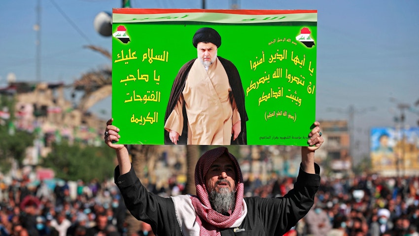 An Iraqi man holds a picture of Shiite cleric and politician Muqtada Al-Sadr during Friday prayers in Baghdad on Dec. 3, 2021. (Photo via Getty Images)