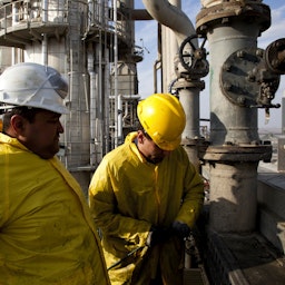 Workers clean a cooling system at the Kar Oil Refinery in Erbil, Iraq on Feb. 29, 2012. (Photo via Getty Images)