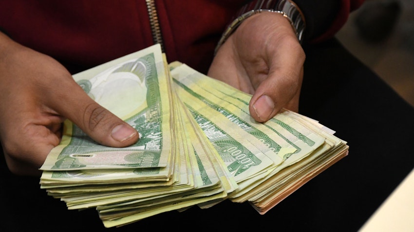 یک دسته دینار عراقی، در دست یک کارمند صرافی؛ ناصریه، عراق، ۳۰ آذر ۱۳۹۹/ ۲۰ دسامبر ۲۰۲۰. (عکس از گتی ایمیجز)