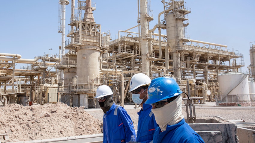 Workers walk past energy installations in Iraq's southern Basra Governorate on Sept. 22, 2021. (Photo via Getty Images)