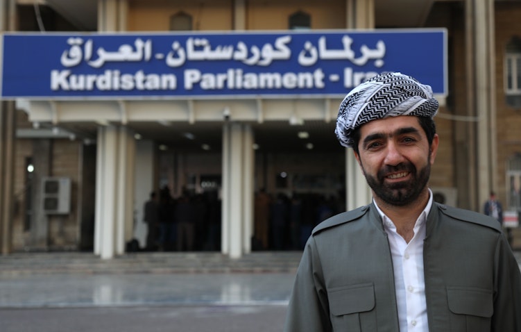 نائب كردي عراقي يقف أمام برلمان إقليم كردستان في أربيل، 14 فبراير/شباط 2019 (الصورة عبر غيتي إيماجز)