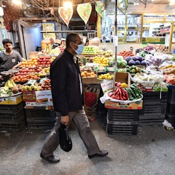 مردی ماسک پوشیده در حال عبور از بازاری در ناصریه؛ عراق، ۳۰ آذر ۱۳۹۹/ ۲۰ دسامبر ۲۰۲۰. (عکس از گتی ایمیجز)
