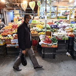A mask-clad man walks past a market in Nasiriyah, Iraq on Dec. 20, 2020. (Photo via Getty Images)
