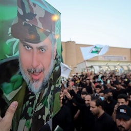 Supporters of Iraqi Shiite cleric Muqtada Al-Sadr carry posters bearing his portrait in Najaf, Iraq on Aug. 27, 2021. (Photo via Getty Images)