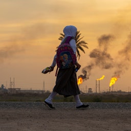 A young girl walks across an oil field in southern Iraq on Dec. 5, 2021. (Photo via Getty Images)