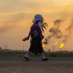 دختری در حال گذر از یک میدان نفتی در جنوب عراق، ۱۴ آذر ۱۴۰۰/ ۵ دسامبر ۲۰۲۱. (عکس از گتی ایمیجز)