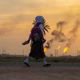 فتاة صغيرة تمشي بمحاذاة حقل نفط في جنوب العراق. 5 ديسمبر/كانون الأول 2021 (الصورة عبر غيتي إيماجز)