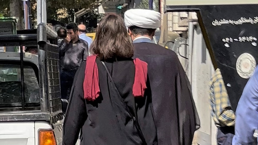 A cleric and a woman without a head scarf walking in the heart of the Iranian capital Tehran, on Oct. 11, 2022. (Photo via Getty Images)