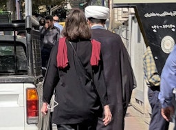 رجل دين وامرأة من دون حجاب يسيران في قلب العاصمة الإيرانية طهران يوم 11 أكتوبر/تشرين الأول 2022. (الصورة عبر غيتي إيماجز)