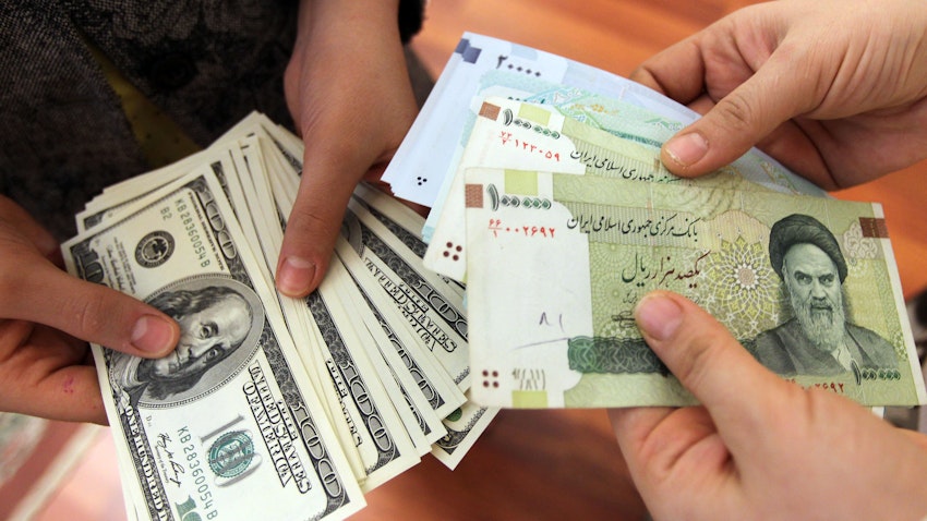 الإيرانيون يتبادلون العملة الأميركية من فئة 100 دولار وأوراق الريال الإيرانية في طهران. 12 يناير/ كانون الثاني 2012 (الصورة عبر غيتي إيماجز)