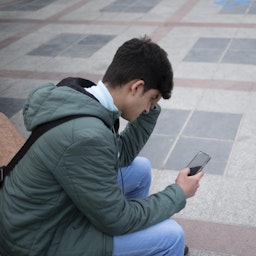 An Iranian young man uses his smartphone to check social media in Tehran, Iran on Feb. 23, 2022. (Photo via Getty Images)