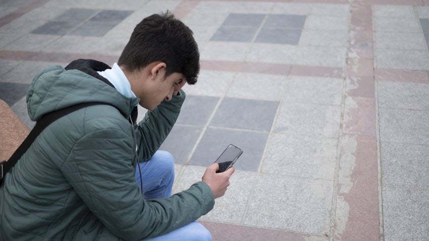 An Iranian young man uses his smartphone to check social media in Tehran, Iran on Feb. 23, 2022. (Photo via Getty Images)