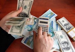 An Iranian dealer counts US 100-dollar bills and Iran's rial banknotes in a currency exchange office in Tehran on Dec. 22, 2010. (Photo via Getty Images)