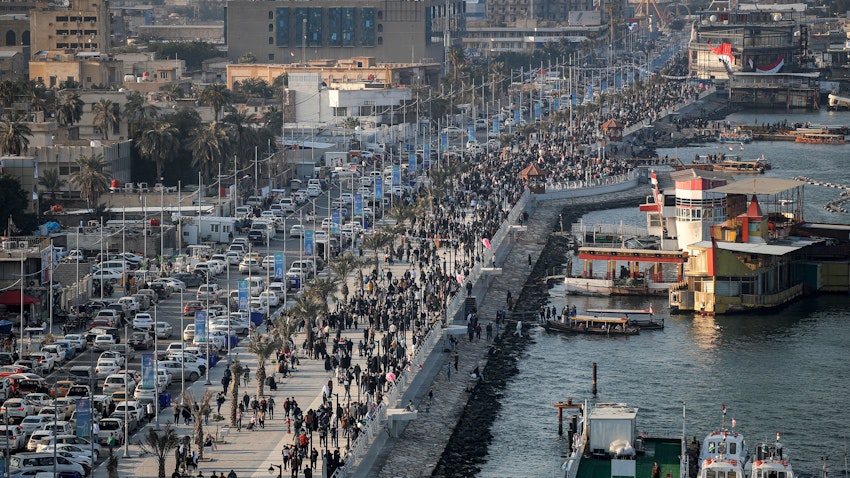أشخاص يمشون على الرصيف على طول الواجهة البحرية لممر شط العرب المائي في البصرة، العراق، يوم 18 يناير/كانون الثاني 2023. (الصورة عبر غيتي إيماجز)