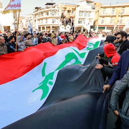 Protestors wave a giant Iraqi flag during protests in Baghdad, Iraq on Jan. 25, 2023. (Photo via Getty Images)
