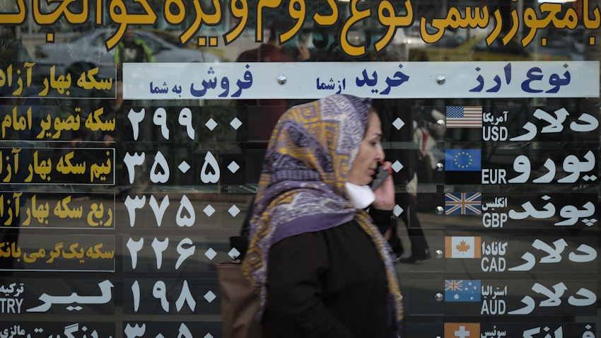 یک زن ایرانی در حال عبور از جلوی یک صرافی در منطقه‌ی تجاری تهران، ۱۹ مهر ۱۳۹۹. (عکس از طریق گتی ایمیجز)