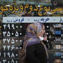 An Iranian woman walks by a currency exchange shop in Tehran’s business district on Oct. 10, 2020. (Photo via Getty Images)