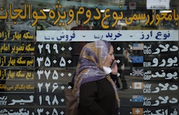 An Iranian woman walks by a currency exchange shop in Tehran’s business district on Oct. 10, 2020. (Photo via Getty Images)